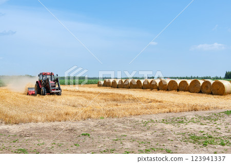 Hokkaido in summer: wheat culm rolls and working machines (Hokkaido image) Hokkaido in summer: wheat culm rolls and working machines (Hokkaido image) 123941337