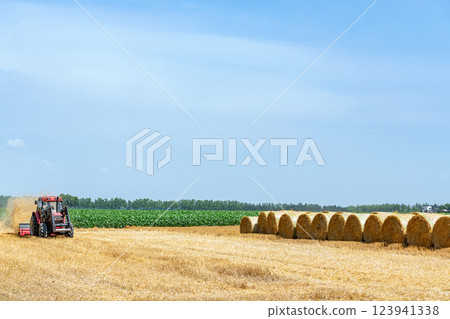 Hokkaido in summer: wheat culm rolls and working machines (Hokkaido image) Hokkaido in summer: wheat culm rolls and working machines (Hokkaido image) 123941338