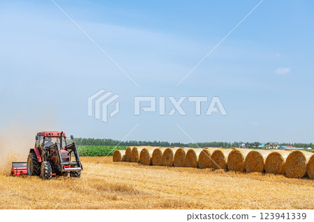 Hokkaido in summer: wheat culm rolls and working machines (Hokkaido image) Hokkaido in summer: wheat culm rolls and working machines (Hokkaido image) 123941339