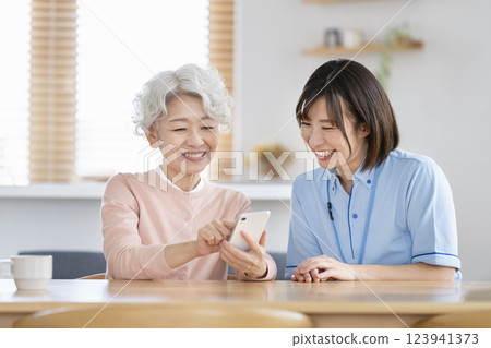 護理人員用智慧型手機與一位老年婦女交談 護理人員用智慧型手機與一位老年婦女交談 123941373