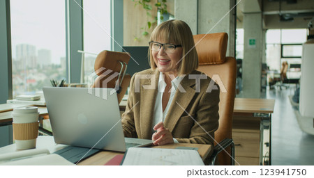 Professional woman giving a presentation during a virtual meeting, holding a notebook and explaining key points. Professional woman giving a presentation during a virtual meeting, holding a notebook and explaining key points. 123941750