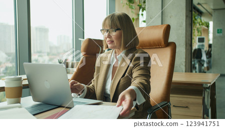 A joyful businesswoman celebrating success in a modern office environment while working on her laptop A joyful businesswoman celebrating success in a modern office environment while working on her laptop 123941751
