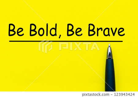 Be Bold and Be Brave text on yellow notepad with pen background Be Bold and Be Brave text on yellow notepad with pen background 123943424