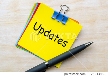 Updates text on yellow notepad with pen background Updates text on yellow notepad with pen background 123943439