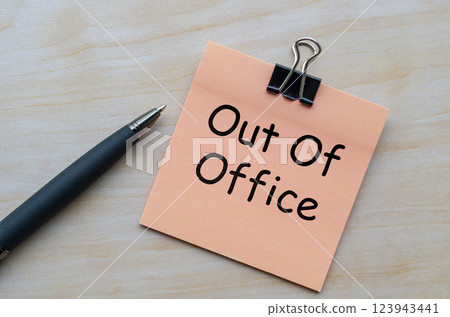 Top view of out of office text on notepad on wooden table 123943441