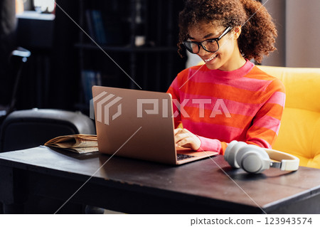 Smiling young African woman is writing in notebook at home. Smiling young African woman is writing in notebook at home. 123943574