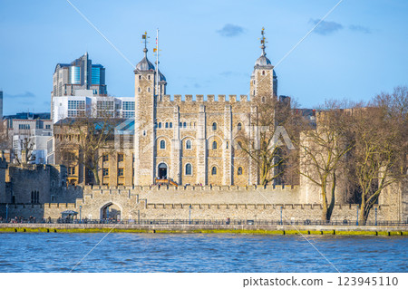 Majestic Tower of London stands proudly on the banks of the River Thames. Visitors admire its medieval architecture and historical significance under a clear blue sky. 123945110