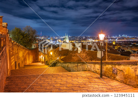 The enchanting staircase of Prague Castle glimmers under the night sky, offering stunning views of the city below, with street lamps casting a warm glow on the cobblestones. The enchanting staircase of Prague Castle glimmers under the night sky, offering stunning views of the city below, with street lamps casting a warm glow on the cobblestones. 123945111