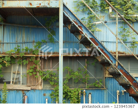 Abandoned apartment building with blue corrugated tin walls scheduled for demolition 123945367