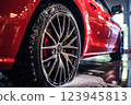 Red sports car being washed with visible droplets 123945813