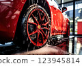 Red sports car being washed with visible droplets 123945814