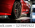 Red sports car being washed with visible droplets 123945922
