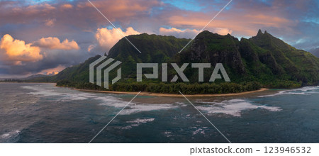 Aerial view of Kauai's Napali Coast with jagged green cliffs, sandy beach, turquoise waters, and a vibrant sunset blending orange and pink hues. Aerial view of Kauai's Napali Coast with jagged green cliffs, sandy beach, turquoise waters, and a vibrant sunset blending orange and pink hues. 123946532