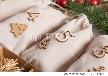 Christmas advent calendar with gift velvet bags and wooden numbers on a white background. Eco-friendly 123947699