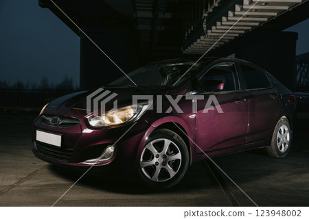 Passenger car at night. Dark burgundy car with headlights on at night Passenger car at night. Dark burgundy car with headlights on at night 123948002