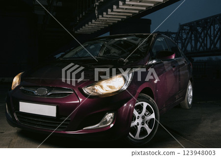 Passenger car at night. Dark burgundy car with headlights on at night 123948003