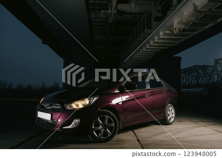 Passenger car at night. Dark burgundy car with headlights on at night Passenger car at night. Dark burgundy car with headlights on at night 123948005