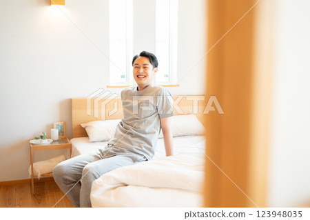 穿著睡衣的男人坐在床上 123948035