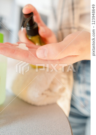 Woman cares for weak nails by pushing back cuticles and applying serum for nail restoration. 123948649