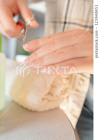 Woman treats weak nails by pushing back cuticles and applying a vitamin serum to restore nail plate health. 123948651