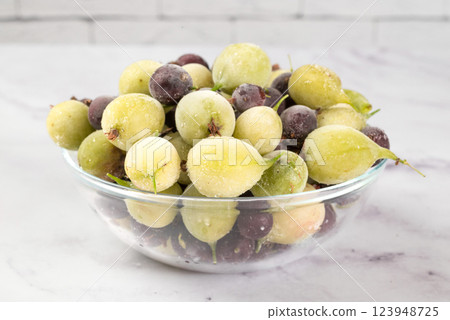 Frozen gooseberry berries in glass dish on a light background. healthy vegetarian dish. dietary product. 123948725