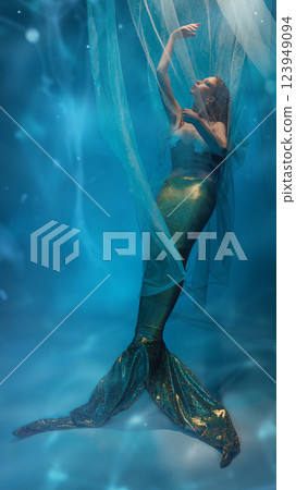 Full-length creative portrait of graceful young woman dressed in mermaid costume, executing tenderness and mystery against ocean-like background 123949094