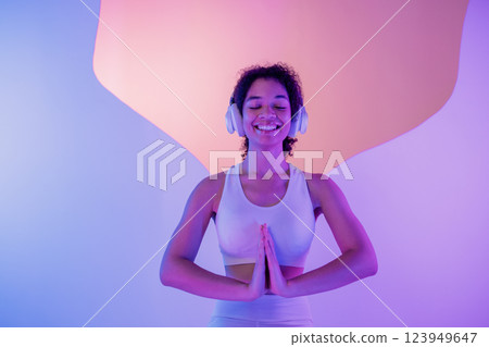 A young African in white sportswear sits in a meditation pose on round platform A young African in white sportswear sits in a meditation pose on round platform 123949647