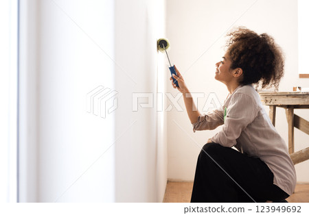 African woman smiles and holds a roller for painting African woman smiles and holds a roller for painting 123949692
