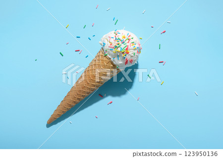 top view of ice cream cone and strewed sprinkles on blue with hard shadow, minimal  summer concept 123950136