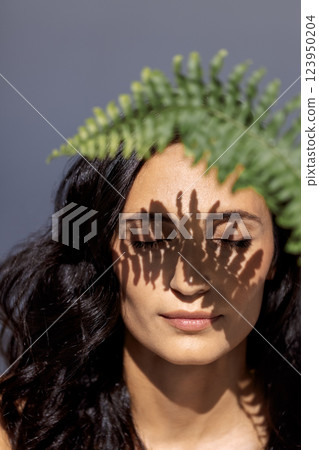 A close-up beauty portrait of a young attractive woman with closed eyes and a green leaf A close-up beauty portrait of a young attractive woman with closed eyes and a green leaf 123950204