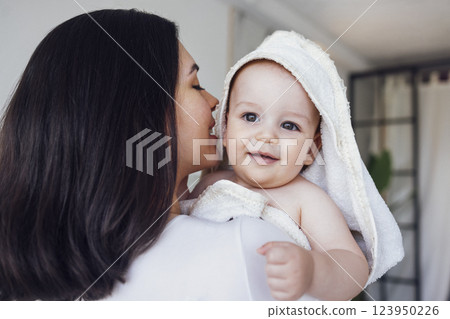 Sweet cute baby sits on the bed next to his mom and plays after bath Sweet cute baby sits on the bed next to his mom and plays after bath 123950226