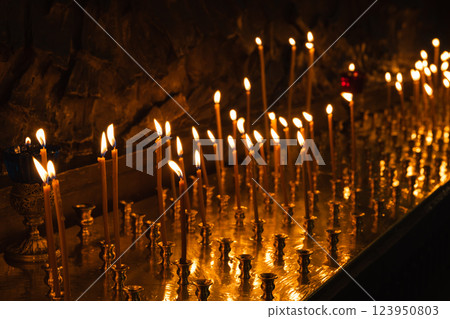 Lit candles glowing dimly in a serene, religious environment 123950803