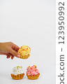 Three shortbread cakes with cream. One cake in a woman's hand. White background. 123950992