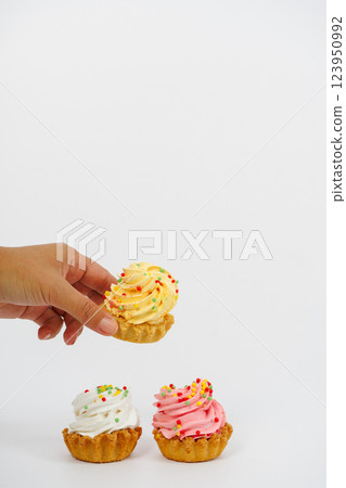 Three shortbread cakes with cream. One cake in a woman's hand. White background. Three shortbread cakes with cream. One cake in a woman's hand. White background. 123950992