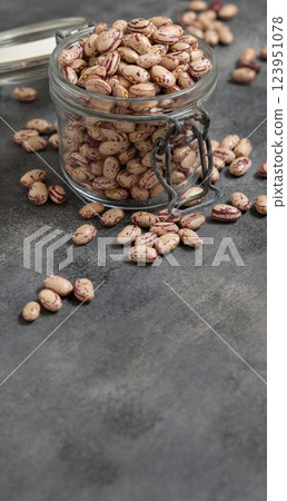 Glass jar full of dried pinto beans on gray closeup, copy space. Traditional Latin American legumes 123951078