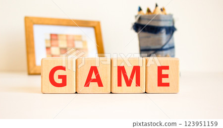 Game symbol. Concept word Game on beautiful wooden blocks. Beautiful picture frame and colored pencils. Beautiful white table white background. Business, lifestyle and game concept. Copy space. 123951159