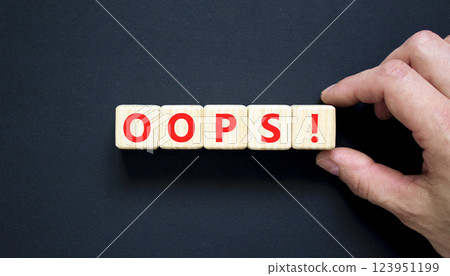 Oops symbol. Concept word Oops on beautiful wooden blocks. Beautiful black table black background. Businessman hand. Business lifestyle oops concept. Copy space. 123951199