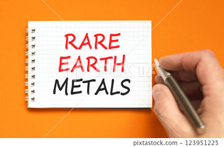 Rare earth metals symbol. Concept words Rare earth metals on beautiful white note. Beautiful orange background. Businessman hand with pen. Business and rare earth metals concept. Copy space. 123951225