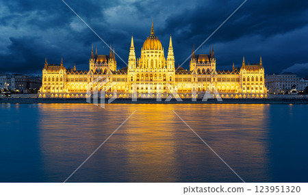 Hungarian parliament building reflecting on danube river at dusk with dramatic sky Hungarian parliament building reflecting on danube river at dusk with dramatic sky 123951320