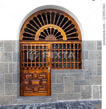 Elegant wooden door and transom with ornate carvings in stone wall 123951361