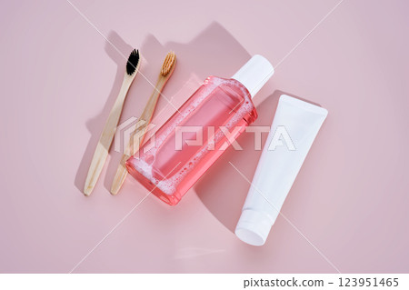 Pink mouthwash, toothpaste and toothbrushes on a pink background. 123951465