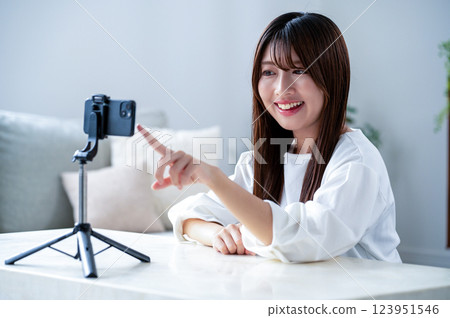 A woman pointing at her smartphone while filming a video A woman pointing at her smartphone while filming a video 123951546