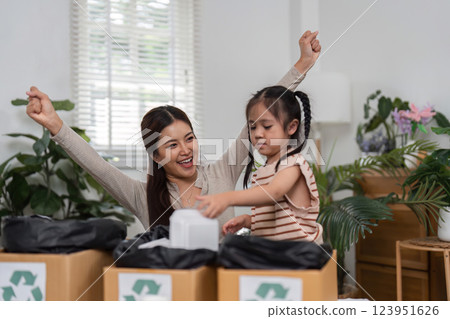 Joyful Recycling and Teaching Moments. A mother celebrates her daughters involvement in a recycling project, emphasizing eco-friendly practices at home. 123951626