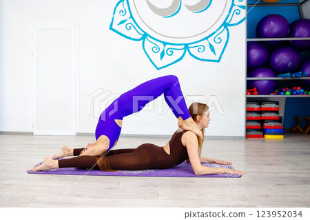 Two women performing an acro yoga pose in a studio 123952034