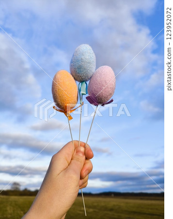 Easter eggs. Easter eggs in hand in the meadow against the background of a bright sky. Vertical Easter eggs. Easter eggs in hand in the meadow against the background of a bright sky. Vertical 123952072