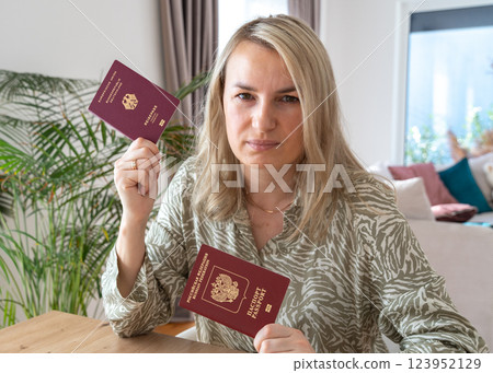 A girl holding two passports, Russian and European, sitting on a chair in the living room. High quality photo 123952129