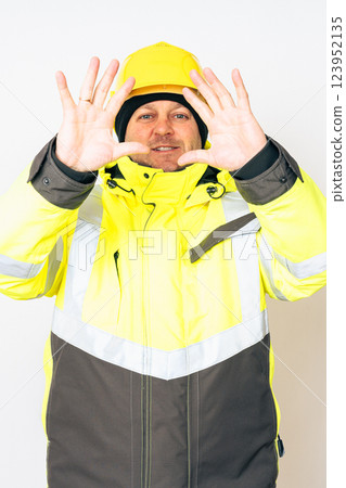 a man wearing a yellow working winter jacket and a yellow safety helmet . High quality photo a man wearing a yellow working winter jacket and a yellow safety helmet . High quality photo 123952135