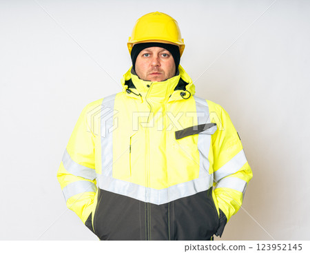 a man wearing a yellow working winter jacket and a yellow safety helmet . High quality photo a man wearing a yellow working winter jacket and a yellow safety helmet . High quality photo 123952145