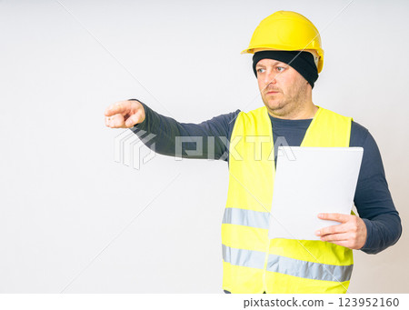 a man in a yellow work vest, overalls and a yellow safety helmet with papers in his hands. High quality photo a man in a yellow work vest, overalls and a yellow safety helmet with papers in his hands. High quality photo 123952160