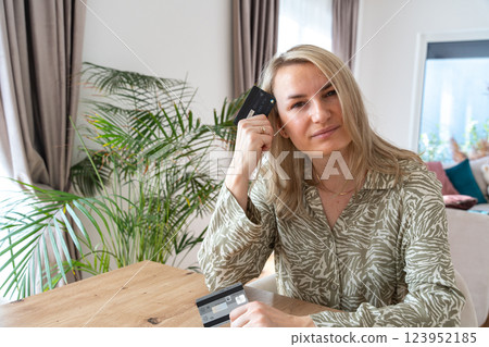 a girl holding credit cards and sitting on a chair in the living room at home. High quality photo a girl holding credit cards and sitting on a chair in the living room at home. High quality photo 123952185